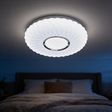 Fluted white dome LED ceiling light glowing above a bed