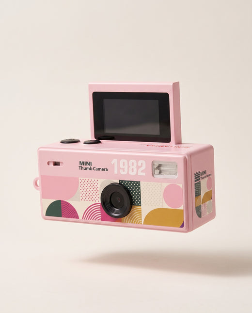 Mini Handheld Flip Camera in pink with its screen flipped up, shown against a cream background
