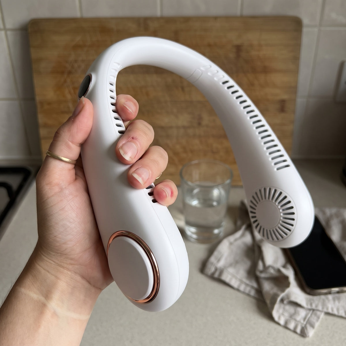 The bladeless neck fan held in one hand, showing its size