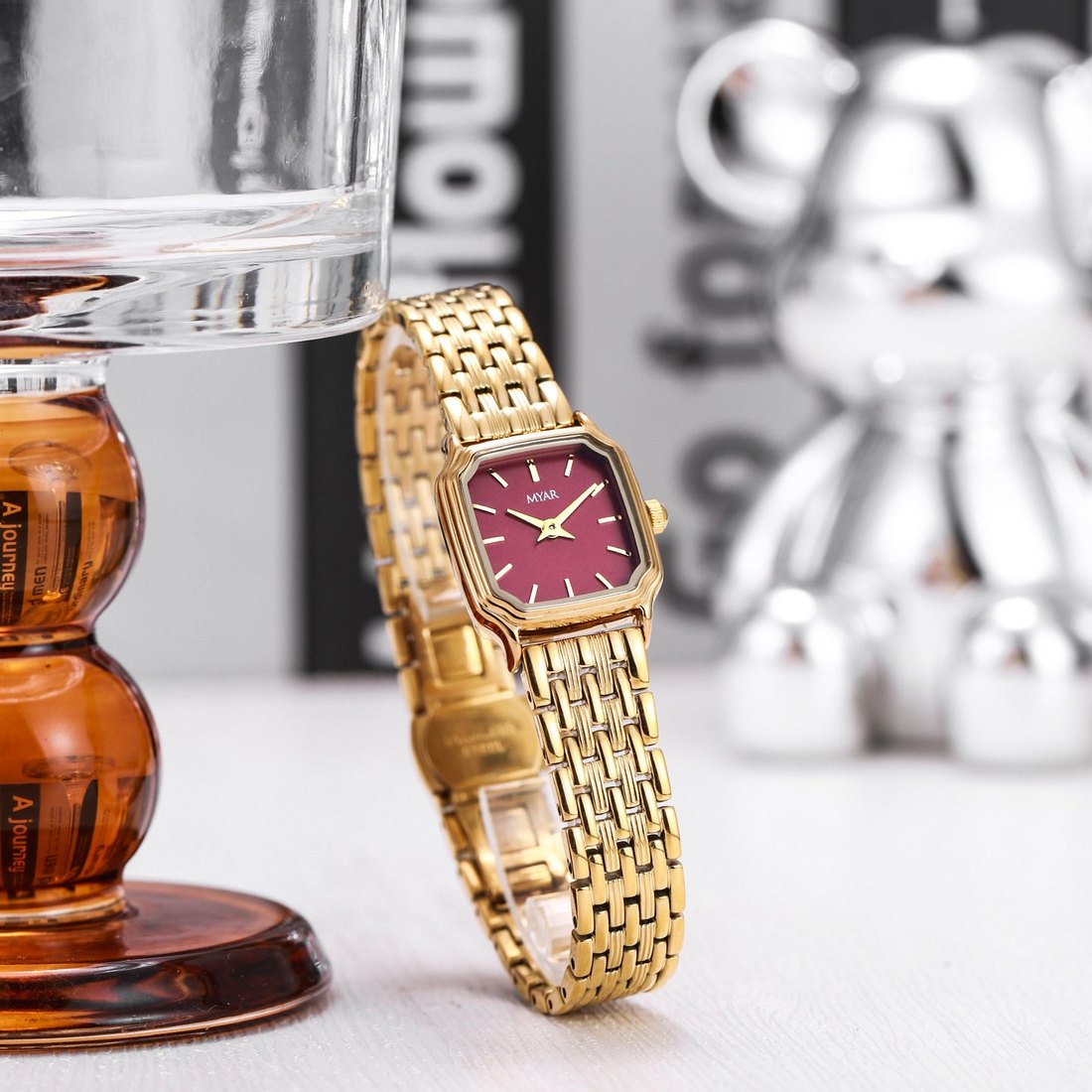 The watch styled beside amber glass