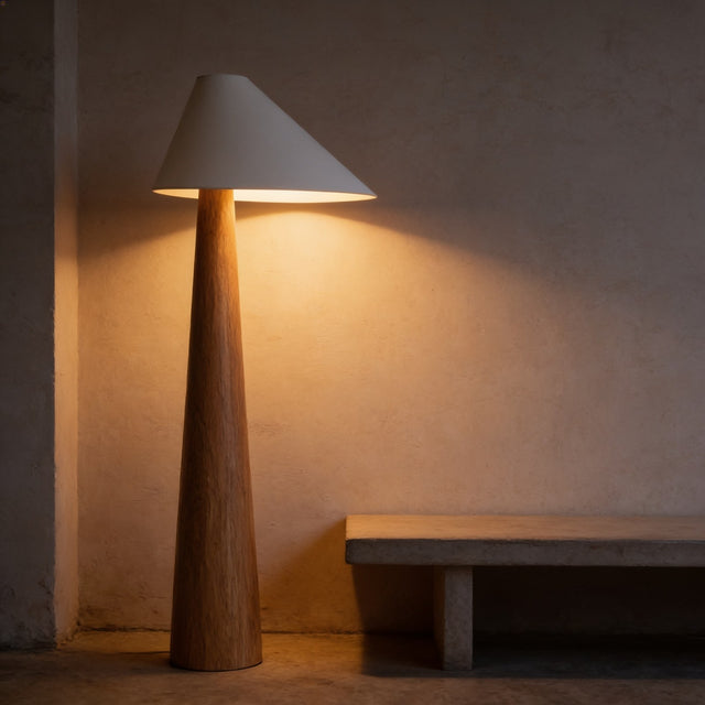 Solid wood tapered floor lamp with a white cone shade against a plaster wall